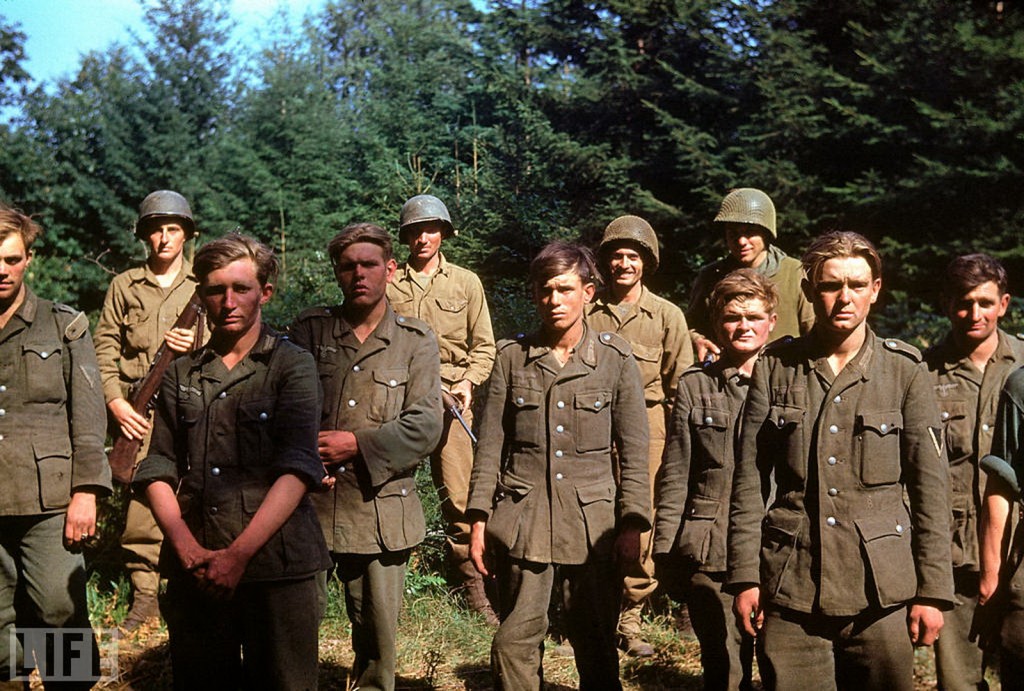 American troops stand guard behind German soldiers captured near the town of Le Gast during the Normandy invasion
